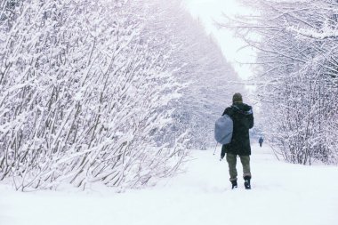 Kış ormanlarında sakallı adam. Çekici, mutlu, sakallı genç bir adam parkta yürüyor..