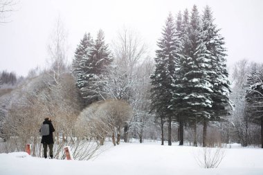 Sokakta kışın giyinmiş bir adam. Turistler oradan geçiyor.
