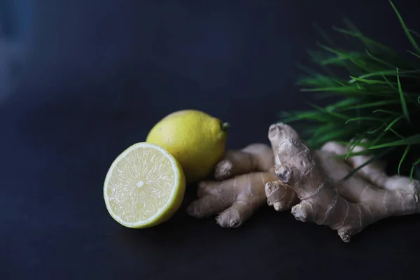Ginger root whole and sliced. Ginger tea with lemon on the dark background. Fresh ginger root on stone background. Vitamins. Top view. Free space for your text.