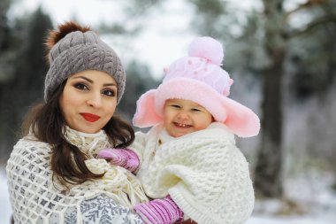 Mutlu bir aile kışın dışarıda karda oynar ve güler. Şehir parkı kış günü