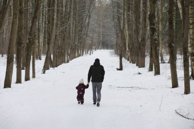Mutlu bir aile kışın dışarıda karda oynar ve güler. Şehir parkı kış günü.