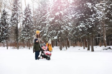 Mutlu bir aile kışın dışarıda karda oynar ve güler. Şehir parkı kış günü.