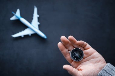 Seyahat konsepti. Elinde manyetik pusula var. El haritasında ve uçak arka planında Retro navigatör. Macera Arkaplanı.