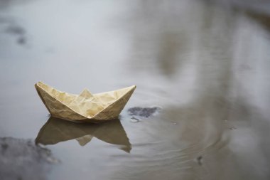 Sokakta kağıttan tekne var. Konsept ilkbaharın başında. Eriyen kar ve su dalgaları üzerinde bir origami teknesi.