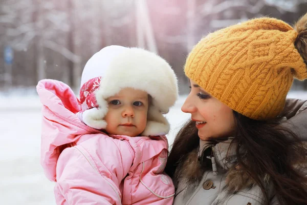 Mutlu bir aile kışın dışarıda karda oynar ve güler. Şehir parkı kış günü.