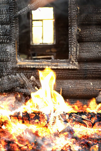 Wooden house after the fire. Coals on the logs. The ashes of the house from fire. Burnt destroyed cottage.