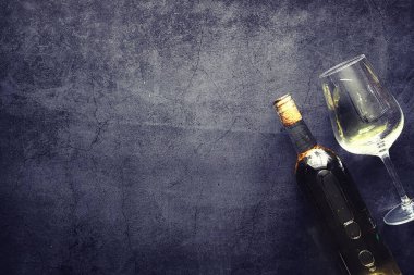 Masada bir bardak kırmızı şarap. Siyah şişe ve bir bardak şarap..