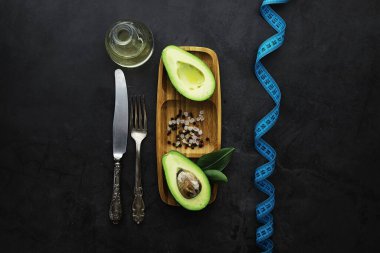 Avokado yemek tarifleri. Tahta kesme tahtasında servis edilen olgun yeşil avokado..