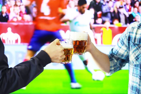 水平保持ラガービールグラスとサッカーゲームの背景をクリックして手 スポーツファンが元気を出す 友人レジャーライフスタイルコンセプト — ストック写真