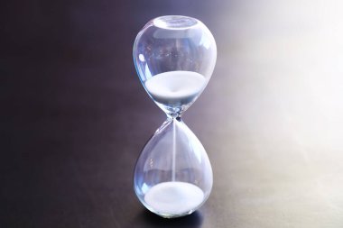 Kum saati ampulleri arasında koşan ve bir geri sayım bitiş tarihine kadar geçen zamanı ölçen, fotokopi alanı olan karanlık bir zemin arka planında..