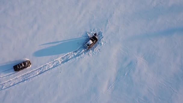 两辆车停放在白雪覆盖的无边无际的草地上的空中景象 — 图库视频影像