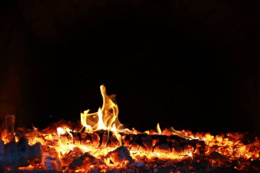 Büyük ateşte yanan kızıl kıvılcımlar uçuşur. Ateş teması üzerine çok soyut bir arka plan. Yanan kömürler, yanan parçacıklar siyah arkaplanda uçuşuyor..