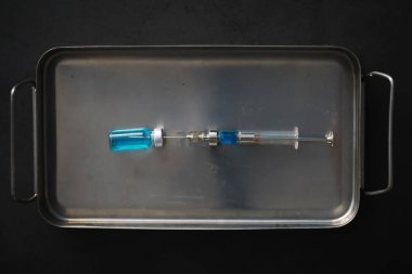 Kimyasal formülün yanındaki mavi arka planda enjeksiyon için küçük kavanozlar ve şırıngalar.