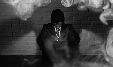 Siyah maskeli ve başlıklı bilgisayar korsanı Monito 'nun önündeki masada.