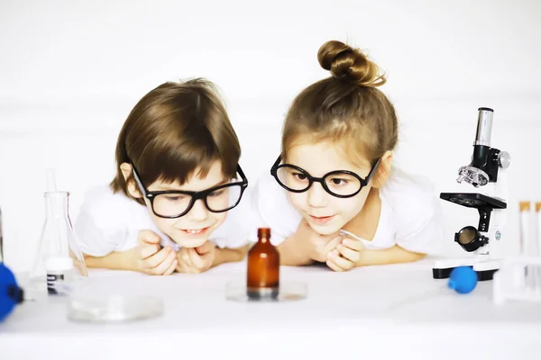 Two cute children at chemistry lesson making experiments isolated on white backgroun