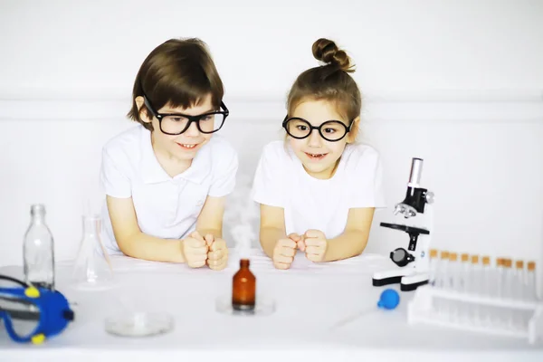 Two cute children at chemistry lesson making experiments isolated on white backgroun