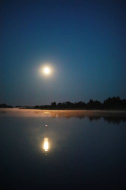 Güzel renkli gece gökyüzü. Parlak ay. Yüksek dağlarda bulutlar ve yıldızlar