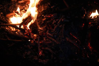 Büyük ateşte yanan kızıl kıvılcımlar uçuşur. Yanan kömürler, yanan parçacıklar siyah arkaplanda uçuşuyor..