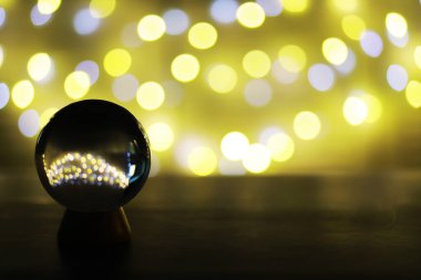 Yerde Bokeh 'le kristal küre var. Renkli ışık saçan cam top, yeni yıl kutlaması konsepti..