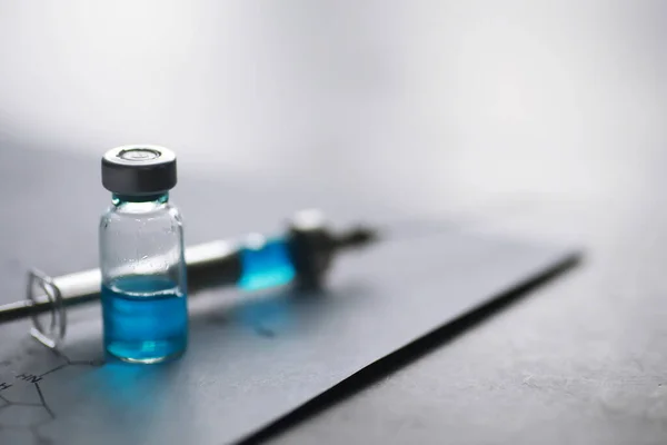 small jars with injection and syringe for injection on blue background near the chemical formul