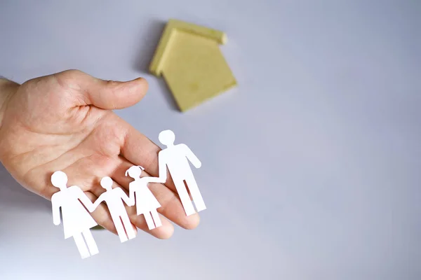 Cutout paper chain family with the protection of cupped hands, concept for security and care. Hands with cut out paper silhouette on table. Family care concept