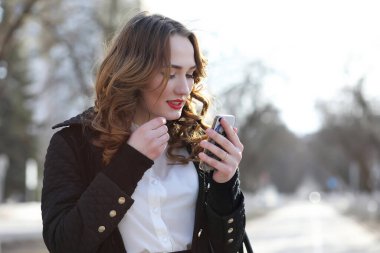 Dışarıda takım elbiseli, cep telefonlu bir iş kadını.