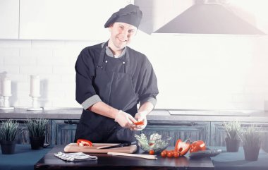 Adam mutfak masasında sebze pişiriyor.