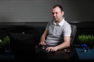 Adam masasında oturuyor ve bir lapto üzerinde çalışıyor.