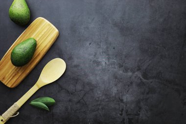 Avokado yemek tarifleri. Tahta kesme tahtasında servis edilen olgun yeşil avokado..