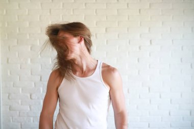 Uzun saçlı genç adam dalgasını sallıyor.