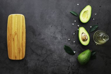 Avokado yemek tarifleri. Tahta kesme tahtasında servis edilen olgun yeşil avokado..