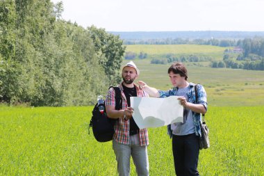 Genç bir adam doğadaki haritaya bakar, böylece kaybolmaz.