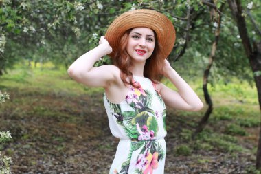 Parkta giysili ve hasır şapkalı kız.