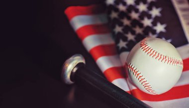 Amerikan geleneksel spor oyunu. Beyzbol mu? Kavram. Amerikan bayrağıyla birlikte beyzbol topu ve sopalar masada..