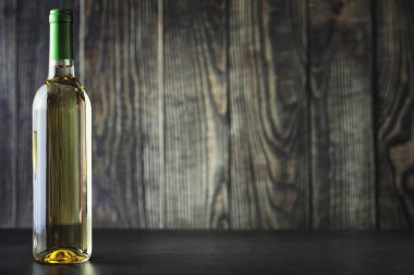 Masada şeffaf beyaz kuru şarap şişesi. Ahşap bir duvar arka plan üzerinde beyaz şarap cam.