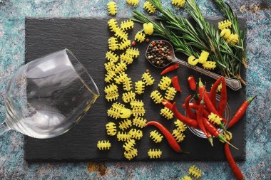 Taş zeminüzerine pişmemiş makarna. Baharatlar ve baharatlar, baharatlı biber ve baharatlarla.