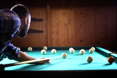 Sakallı bir adam büyük bir bilardo oynar. 3,5 metrelik havuzda parti. Kulüp oyununda erkekler için bilardo. Elinde ıstakayla bir adam piramidi kırar.