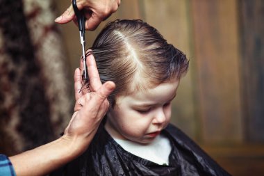 Küçük bir çocuk kuaförün parlak duygularıyla süslenir.
