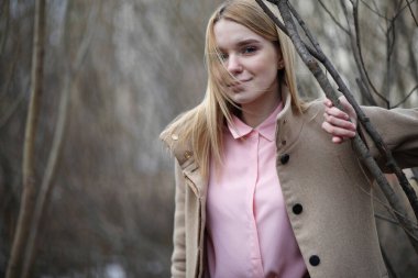 Soğuk, güneşli bir günde, şehir parkında tatlı bir sarışın.