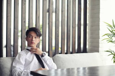 Genç bir Asyalı işadamı bir kafede ortak bekliyor. Bir kafede Koreli genç bir adam telefonda konuşuyor.