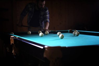 Sakallı bir adam büyük bir bilardo oynar. 3,5 metrelik havuzda parti. Kulüp oyununda erkekler için bilardo. Elinde ıstakayla bir adam piramidi kırar.