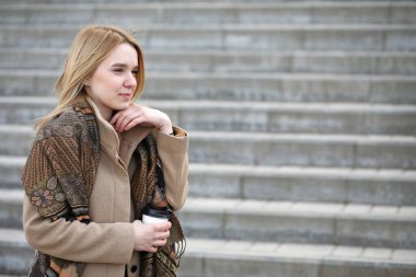 Şehirdeki sevimli sarışın merdivenlerde kahve içiyor.