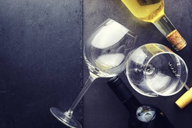 Masada bir bardak kırmızı şarap. Siyah şişe ve bir bardak şarap..