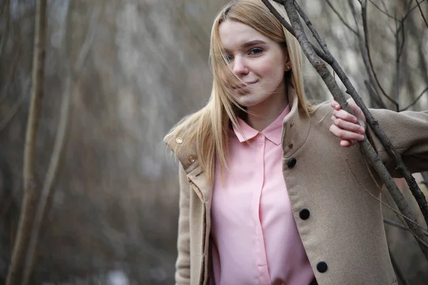 Soğuk, güneşli bir günde, şehir parkında tatlı bir sarışın.