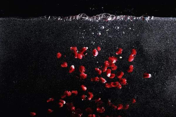 Olgun tatlı nar tohumlarına su damlaları düşer. Metnin için kopyalama alanı olan taze nar arkaplanı. Vejetaryen ve vejetaryen kavramı.