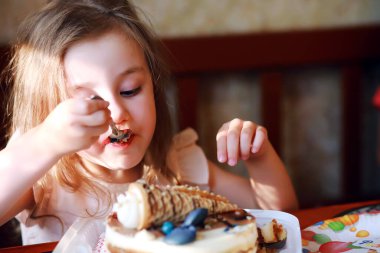 Çocuklar doğum gününü evde pasta ve balonlarla kutluyor.