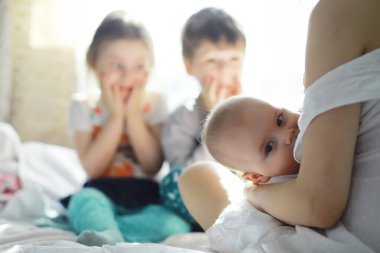 Annelik konsepti. Genç bir anne küçük bebeğini besler. İlk yem ve emzirme. Beyaz elbiseli büyük bir aile..