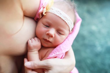 Yeni doğmuş bir bebek annesinin kollarında yatıyor. Avrupa görünümlü güzel bebek uyuyor.