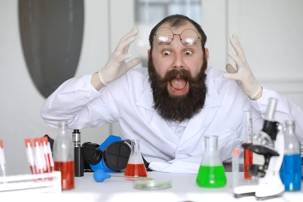 Chemist crazy. A mad scientist conducts experiments in scientific laboratory. Performs research using a microscope.