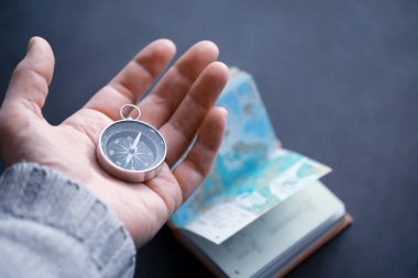 Seyahat konsepti. Elinde manyetik pusula var. El haritasında ve uçak arka planında Retro navigatör. Macera Arkaplanı.